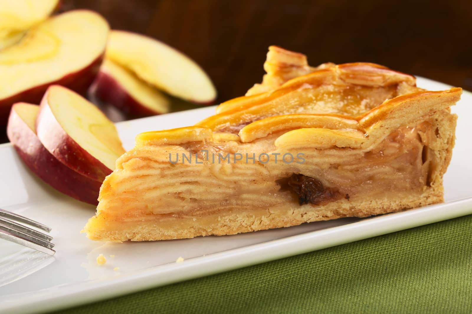 A slice of delicious apple pie with apple slices in the back (Selective Focus, Focus on the left front part)