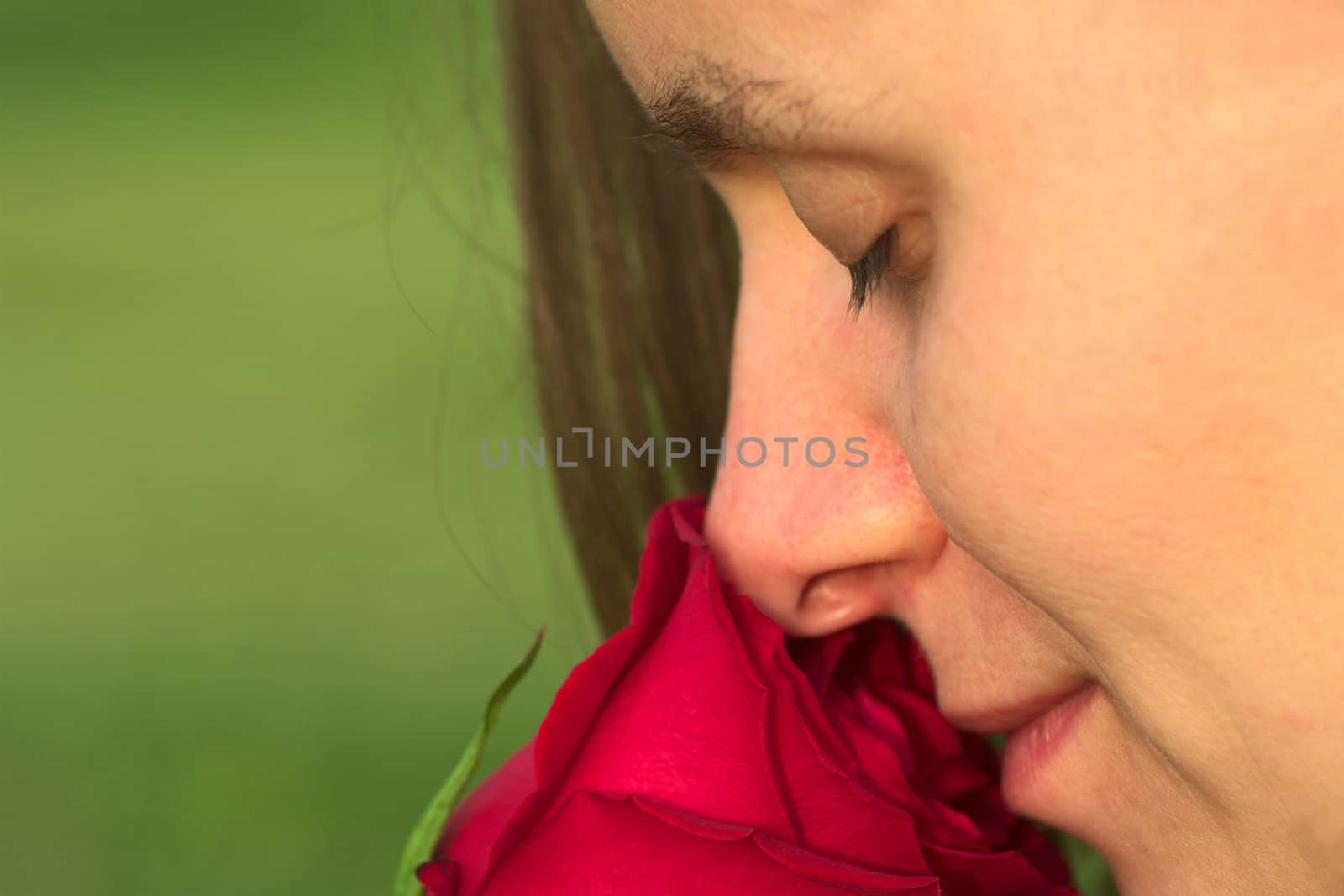 Young Caucasian woman smelling at a red rose with closed eyes (Very Shallow Depth of Field) 