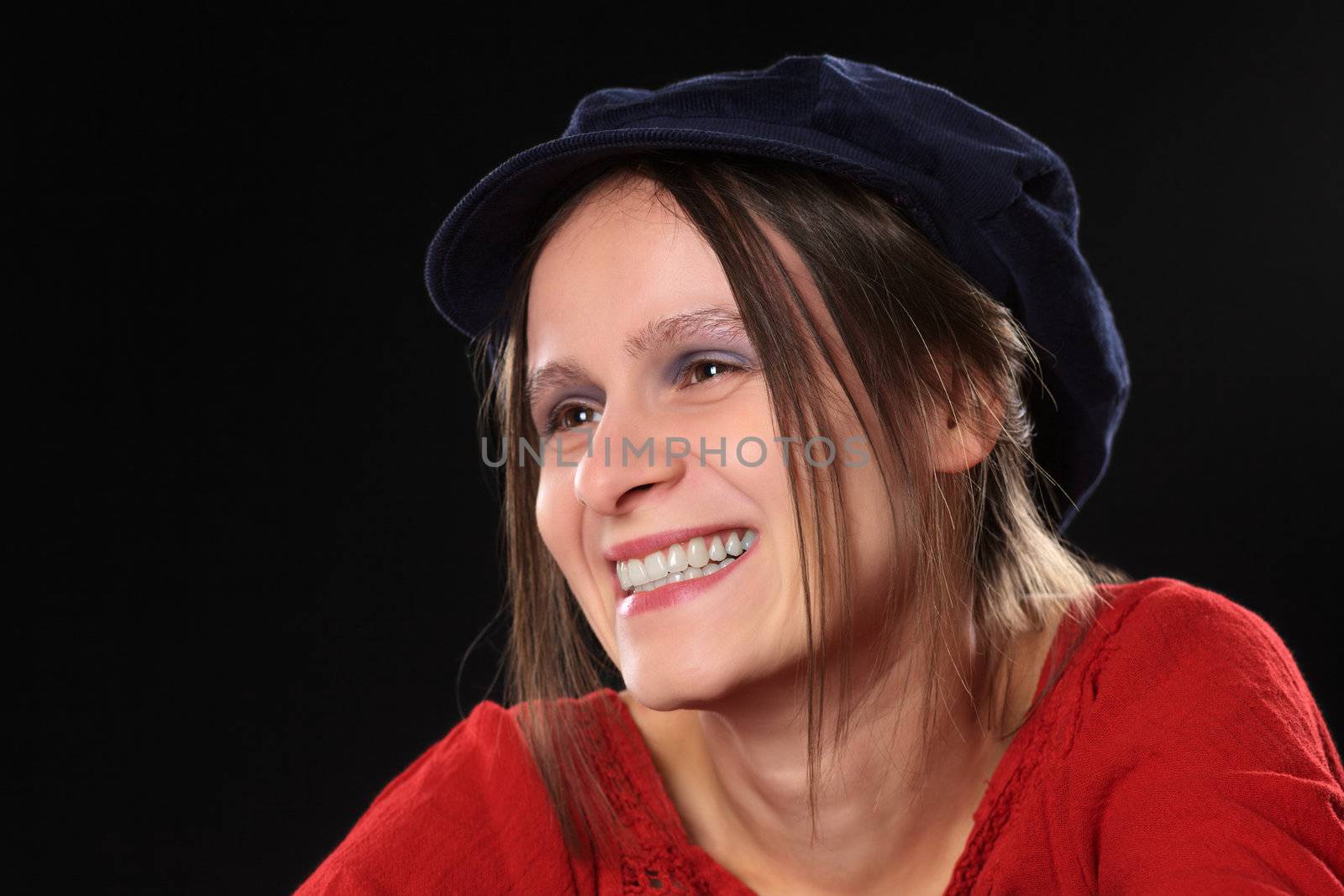 Smiling beautiful young Caucasian woman with a blue gatsby cap (Selective Focus, Focus on the left eye)