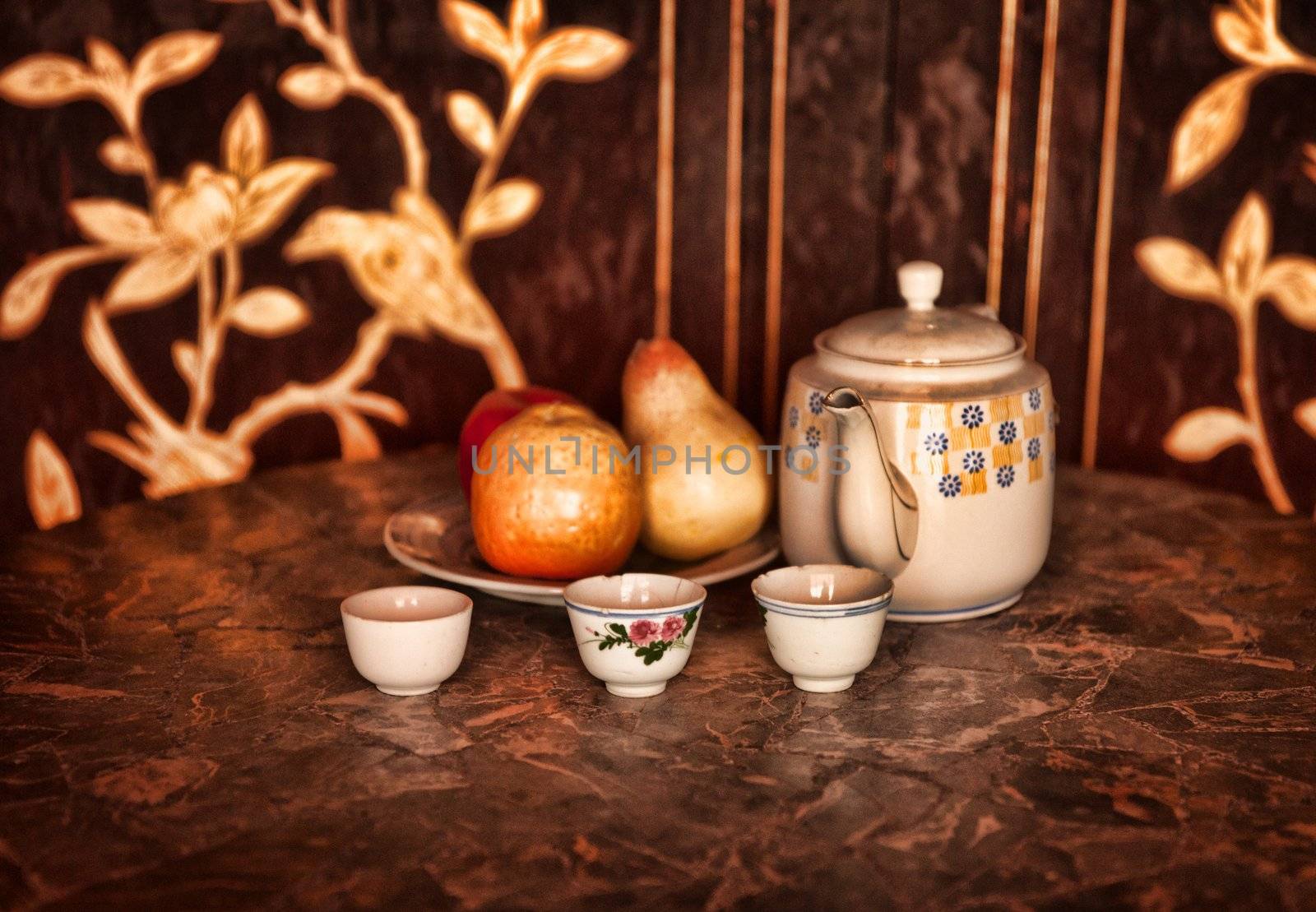 still life low key image of a tea pot cups and fruit