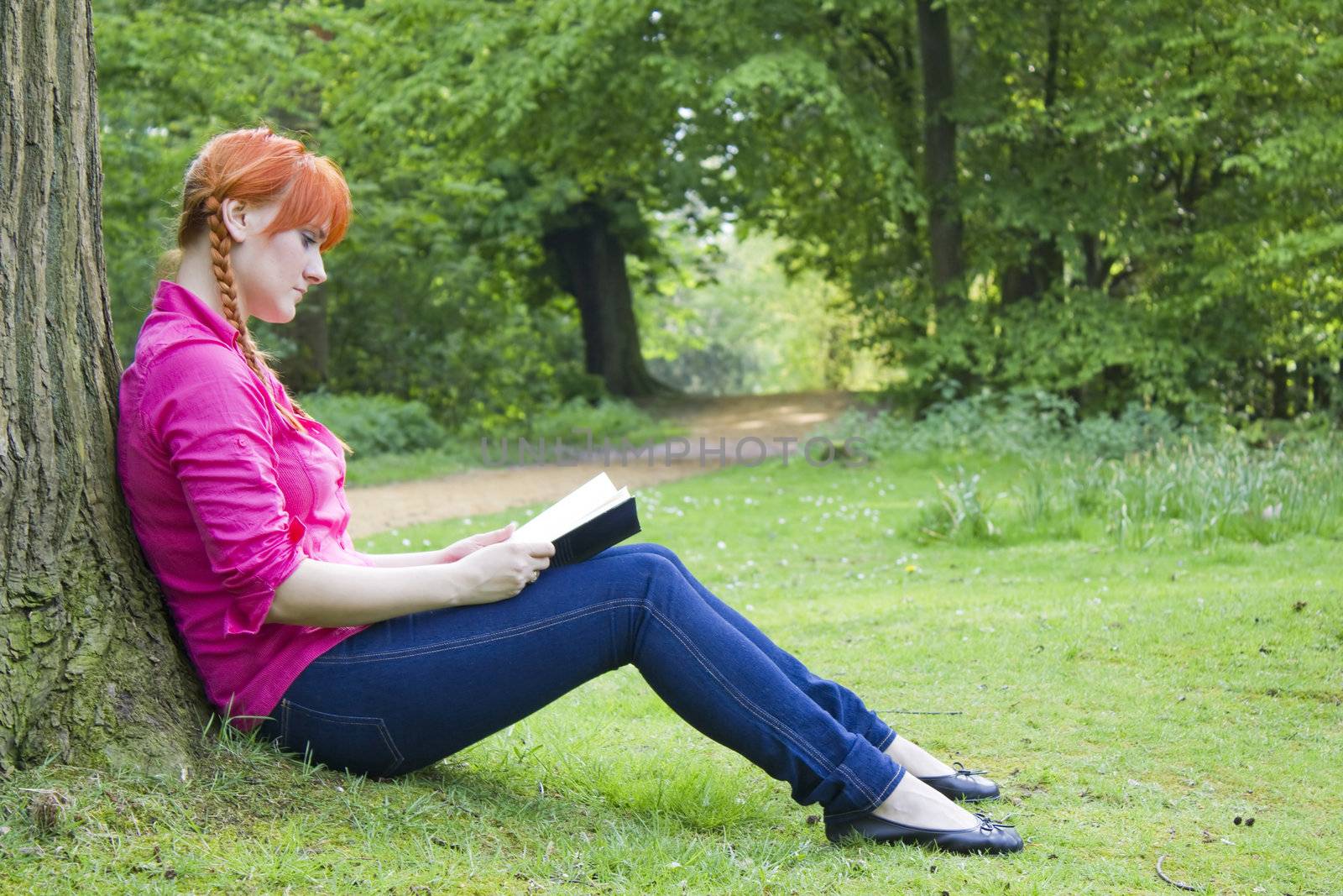 Young beautiful girl with red hair reading a book by miradrozdowski