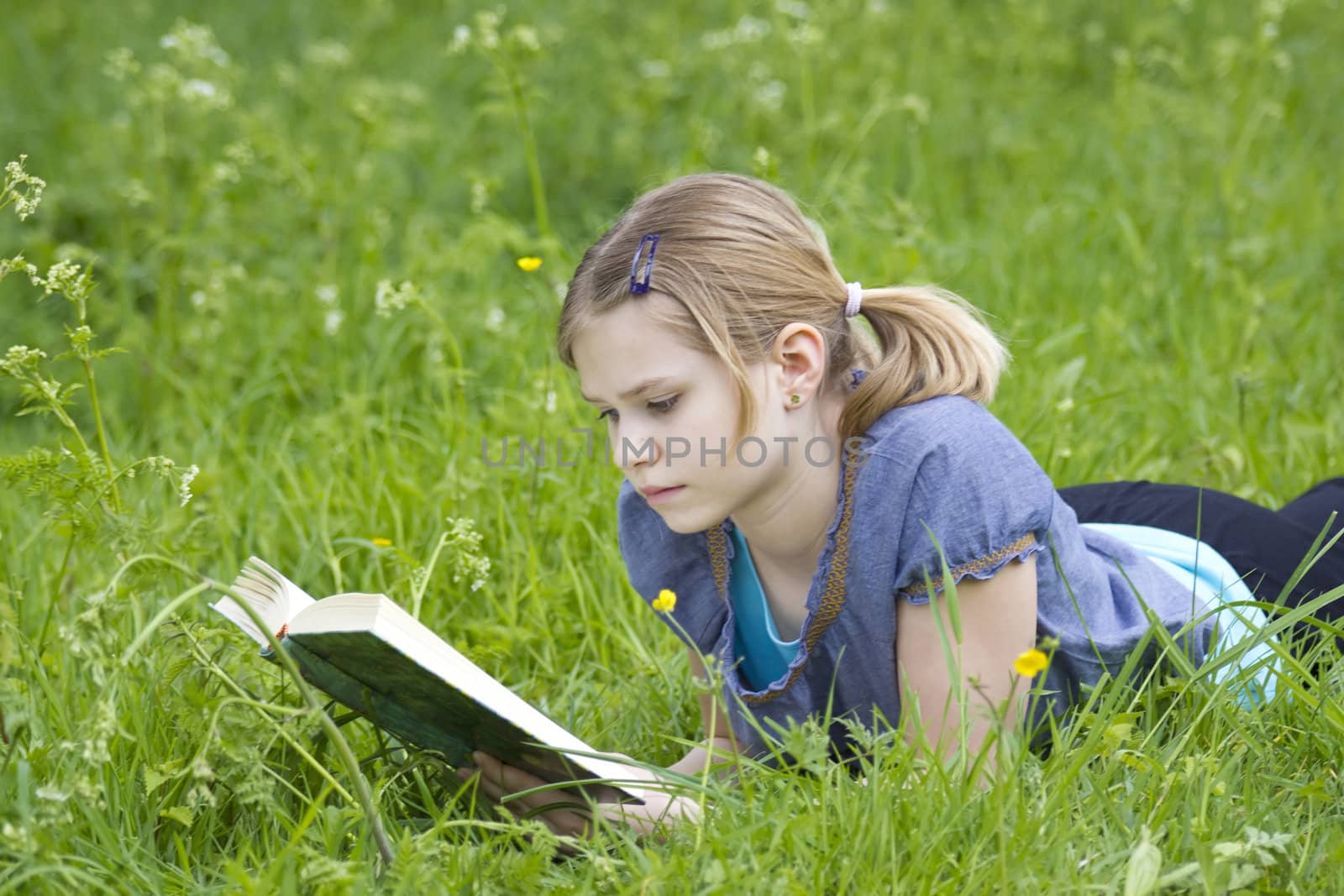 A little girl reading a book outdoor by miradrozdowski