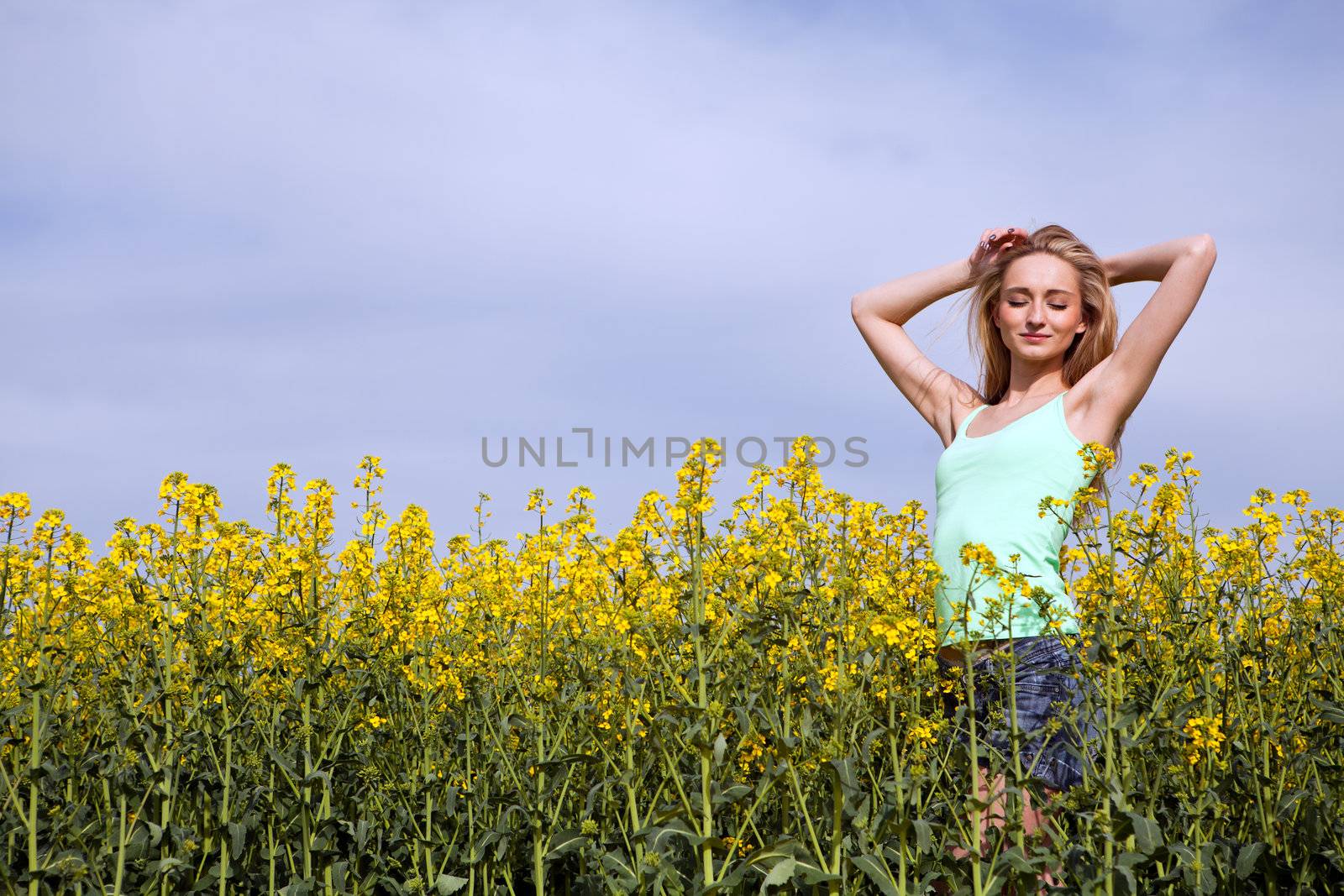 young beautiful blonde girl in a field in summer happy