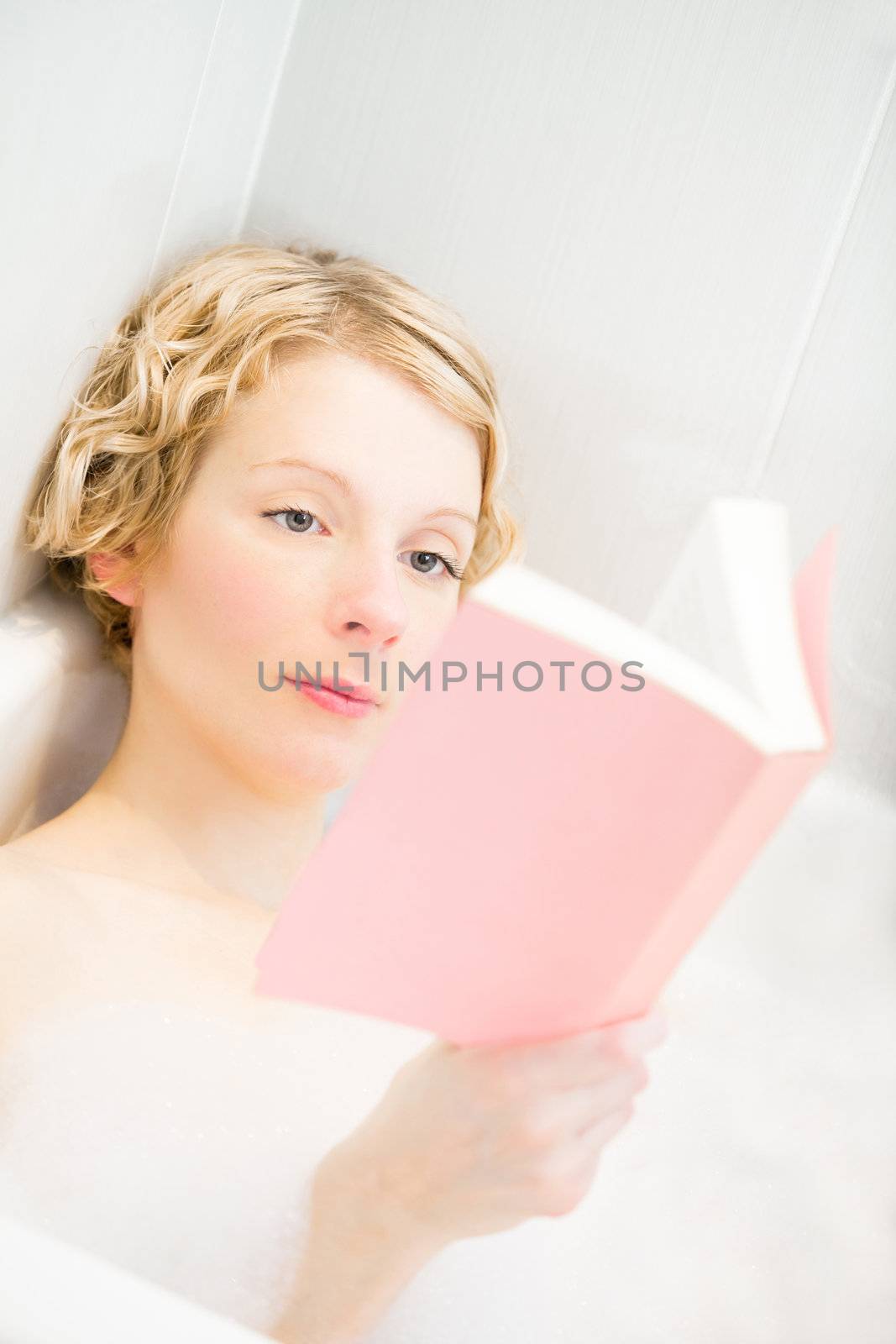 Young woman reading a book in the bath