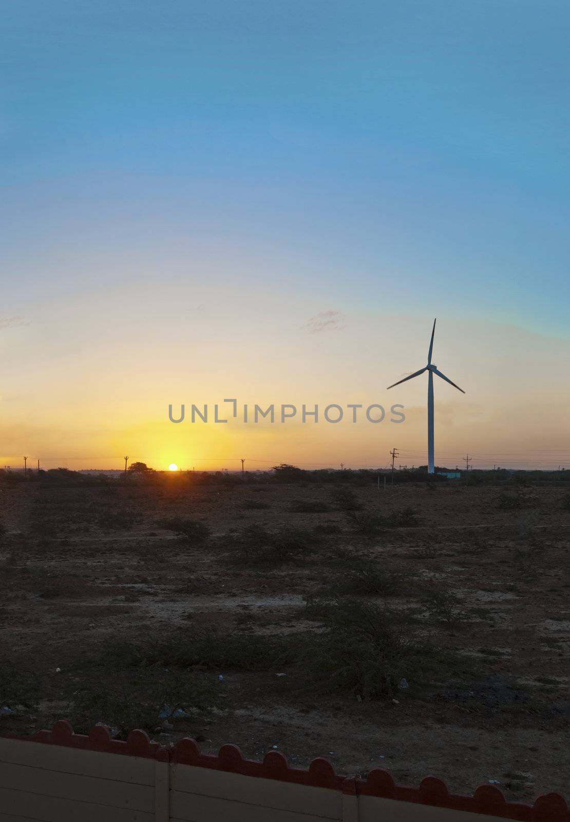 Vertical image of barren land on the approach to Dwarka in Gujarat India. The sea breeze from the Arabian Sea is taken advantage of on plains with installation of wind powered generators for local infrastructure in the form of electrical power