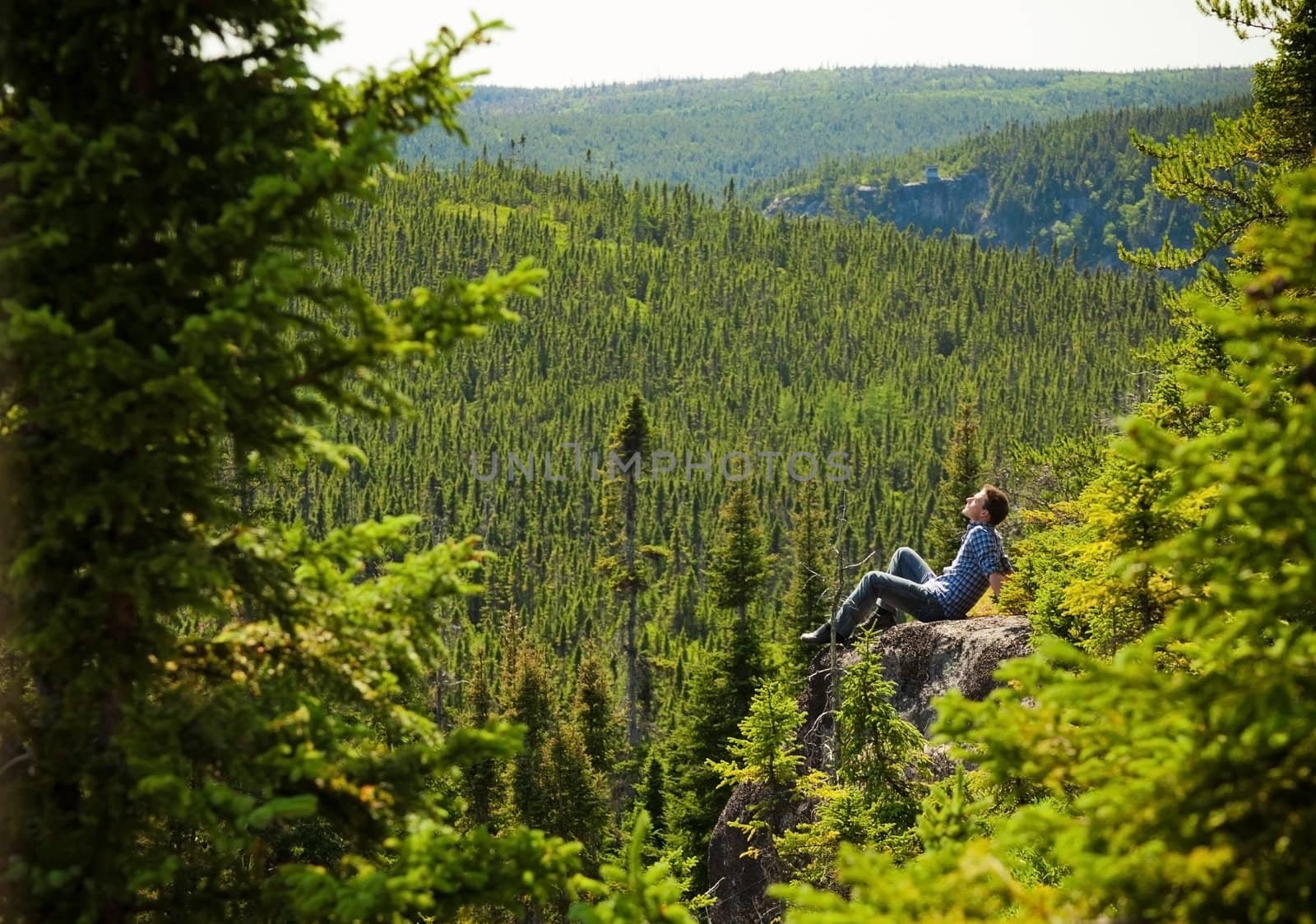 Young man relaxing on a rock in the middle of the nature