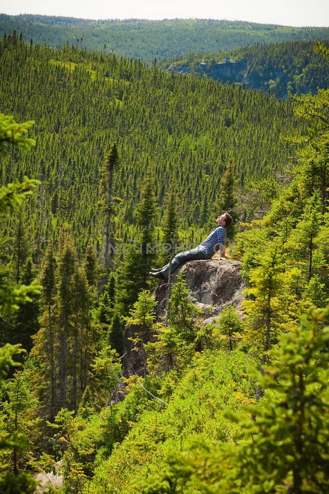 Young man relaxing on a rock in the middle of the nature