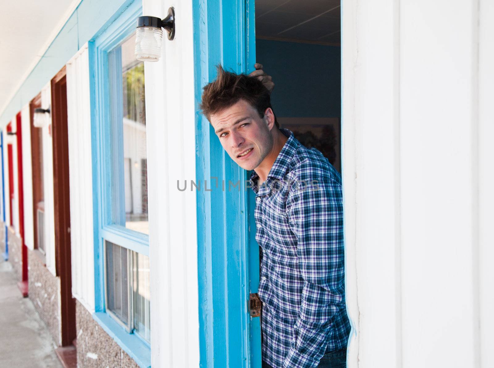 Worried young man looks out of the ugly motel room