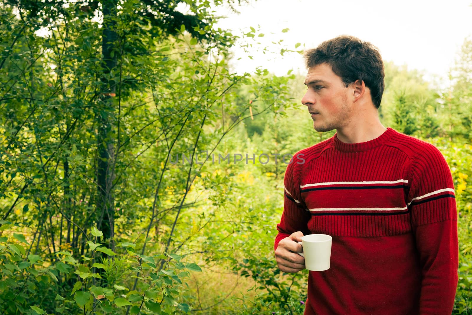 Man lost in nature with a mug of coffee