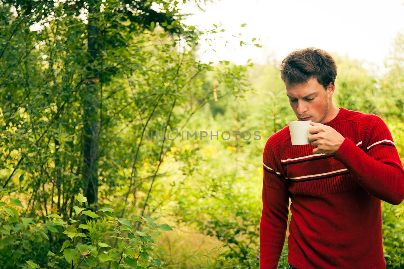 Young man in nature with a mug of coffee by aetb