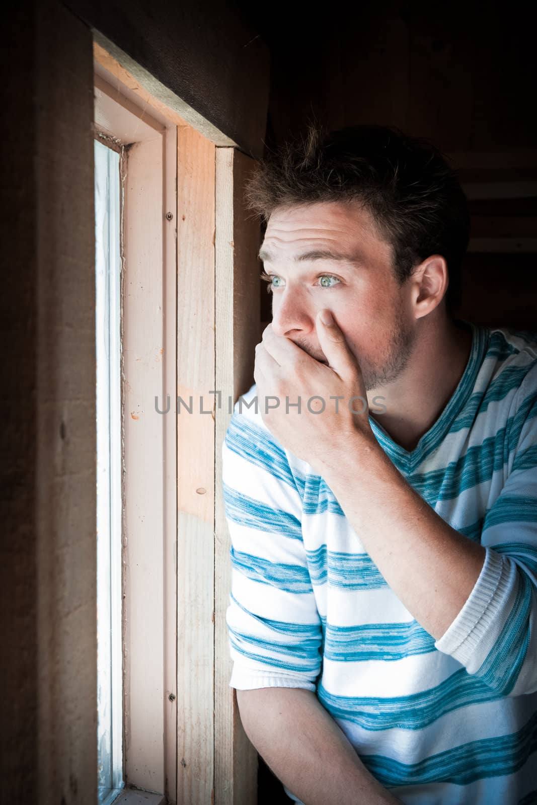 Young man startled by something he saw by looking at the window