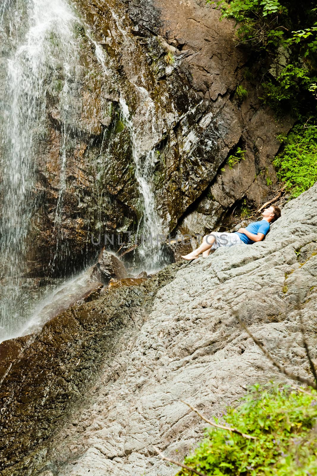 Young man near a waterfall in the forest