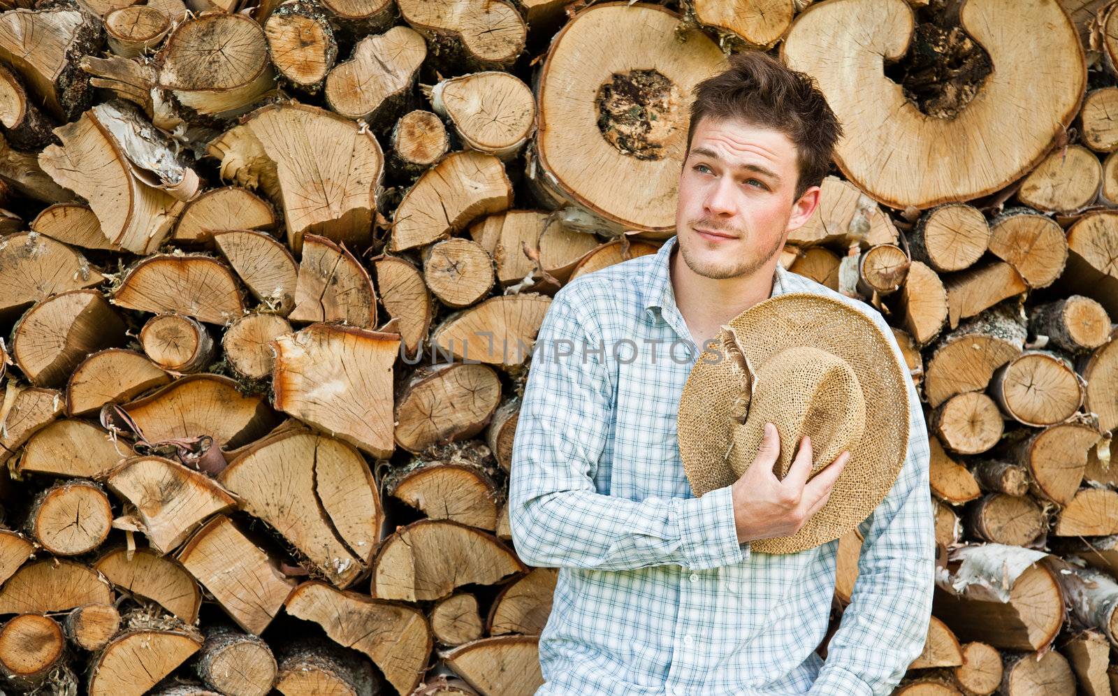Woodcutter with straw hat on a background of wood