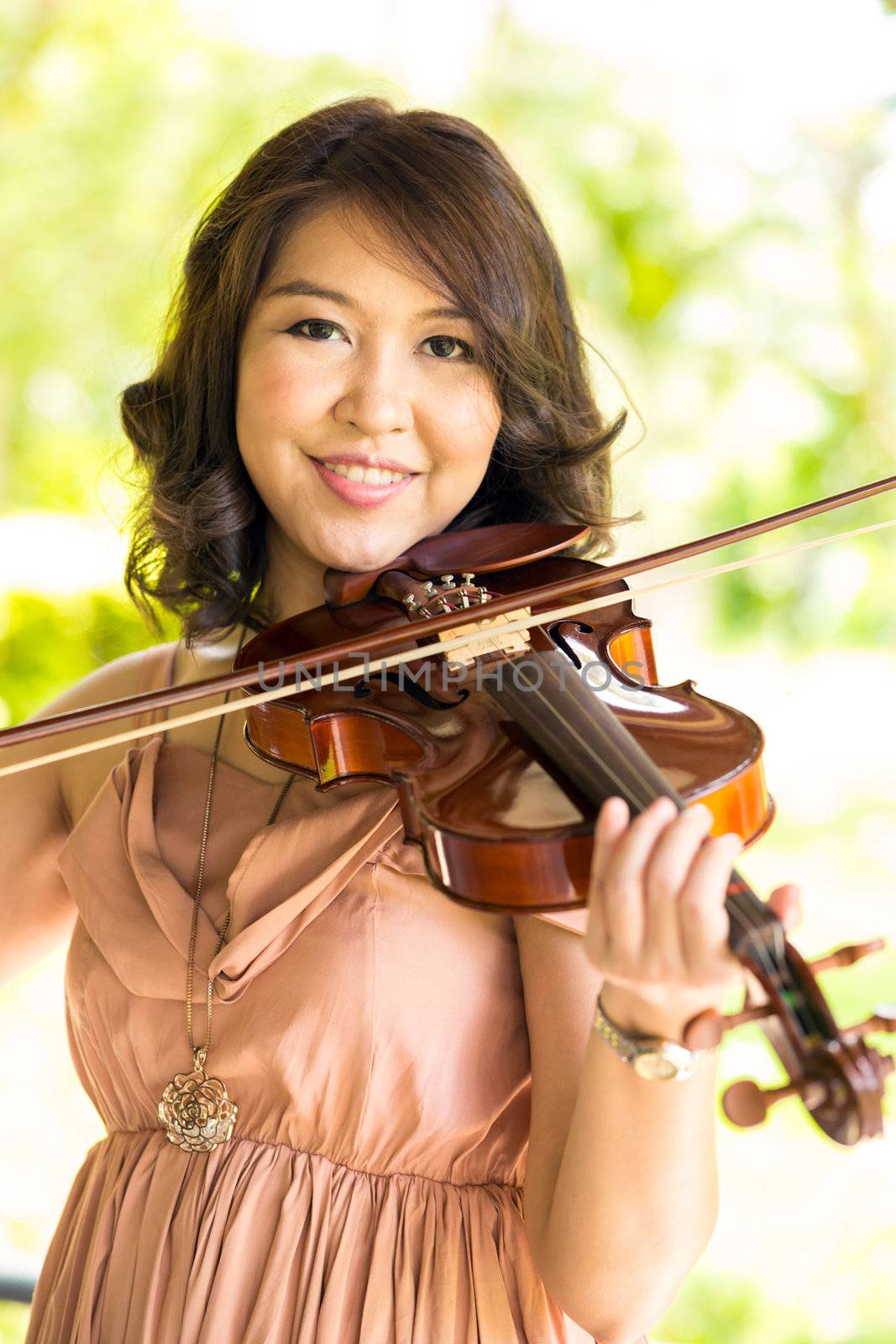 Young woman playing violin in garden