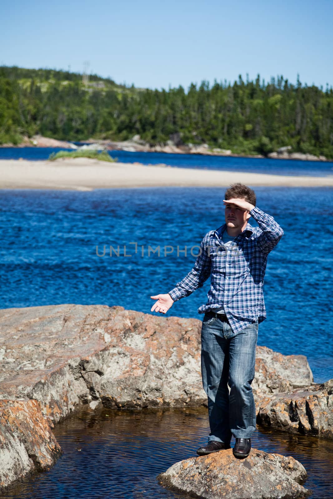 Young man lost and standing on a rock in the middle of the water