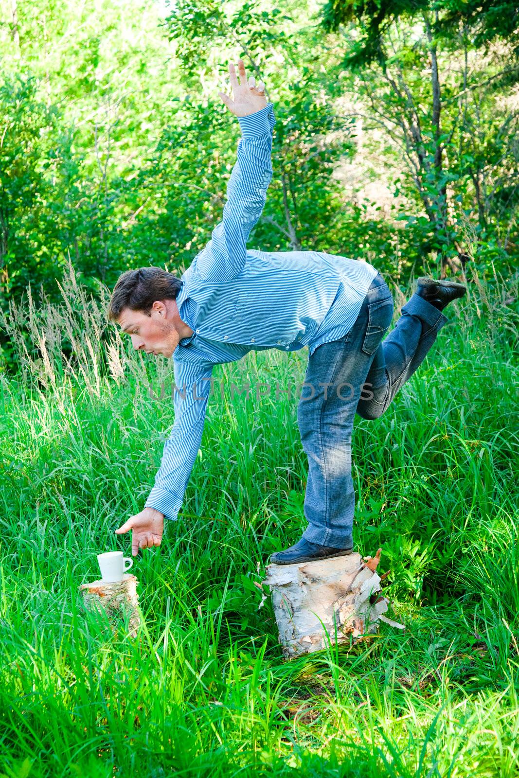 Young businessman in nature doing acrobatic poses