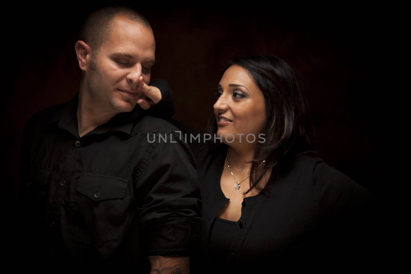 Happy Mixed Race Couple Flirting with Each Other Portrait Against A Black Background.