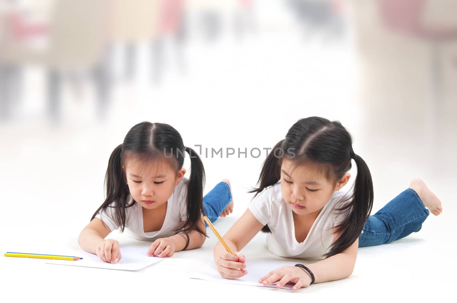 Little Asian girls drawing, lying on floor
