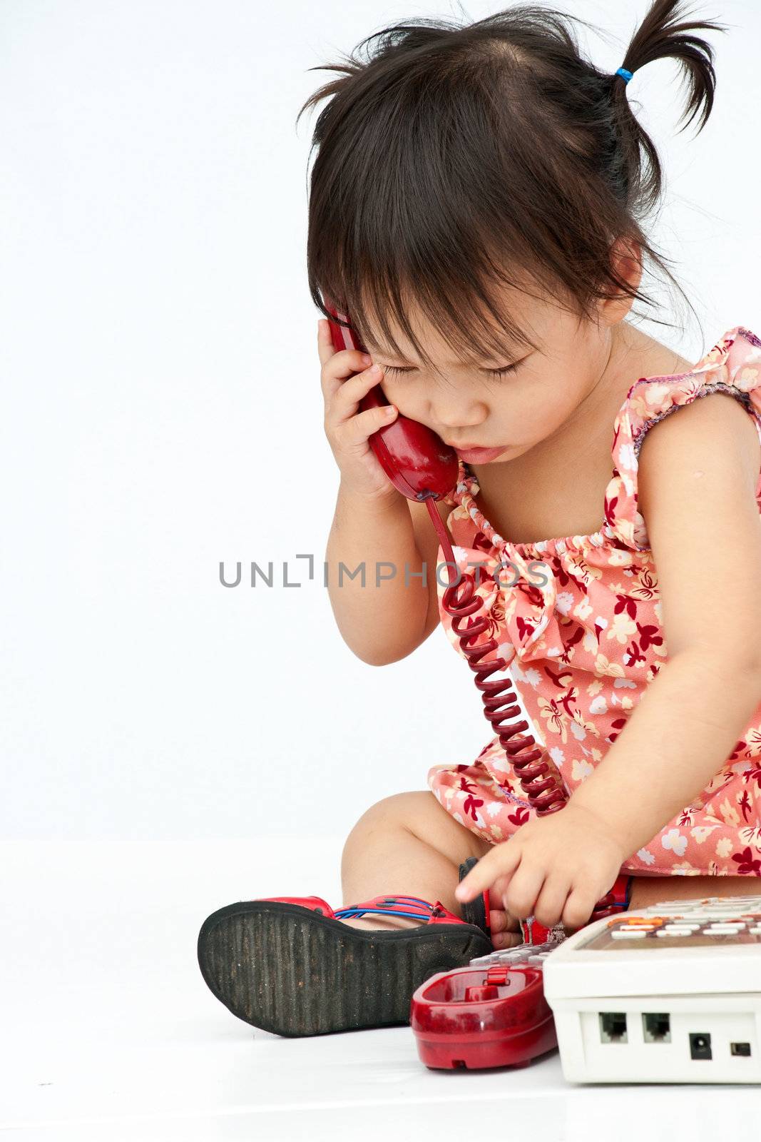 Baby dialing old beige phone calling mom isolated on white