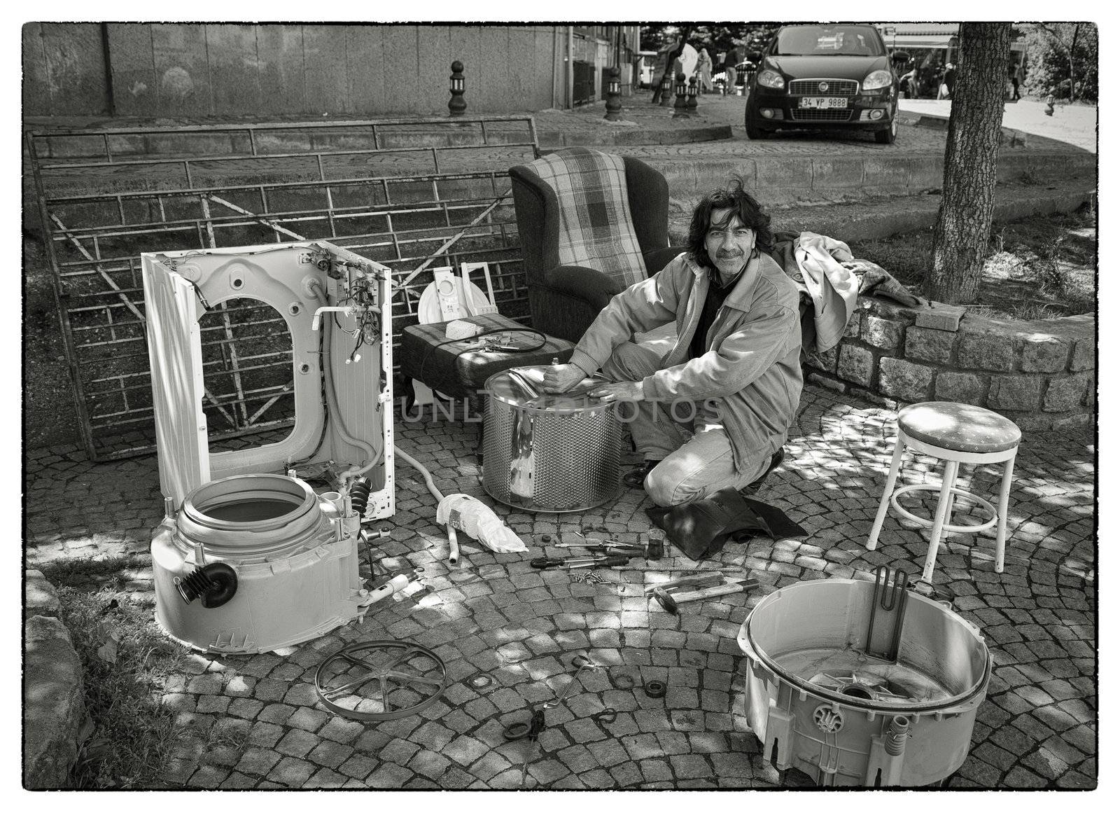 WASHING MACHINE BUILDER, USKUDAR, ISTANBUL, TURKEY, APRIL 16, 2012: Dexterous Turkish man building new washing machines out of spare parts from old ones. His business take place in the street.