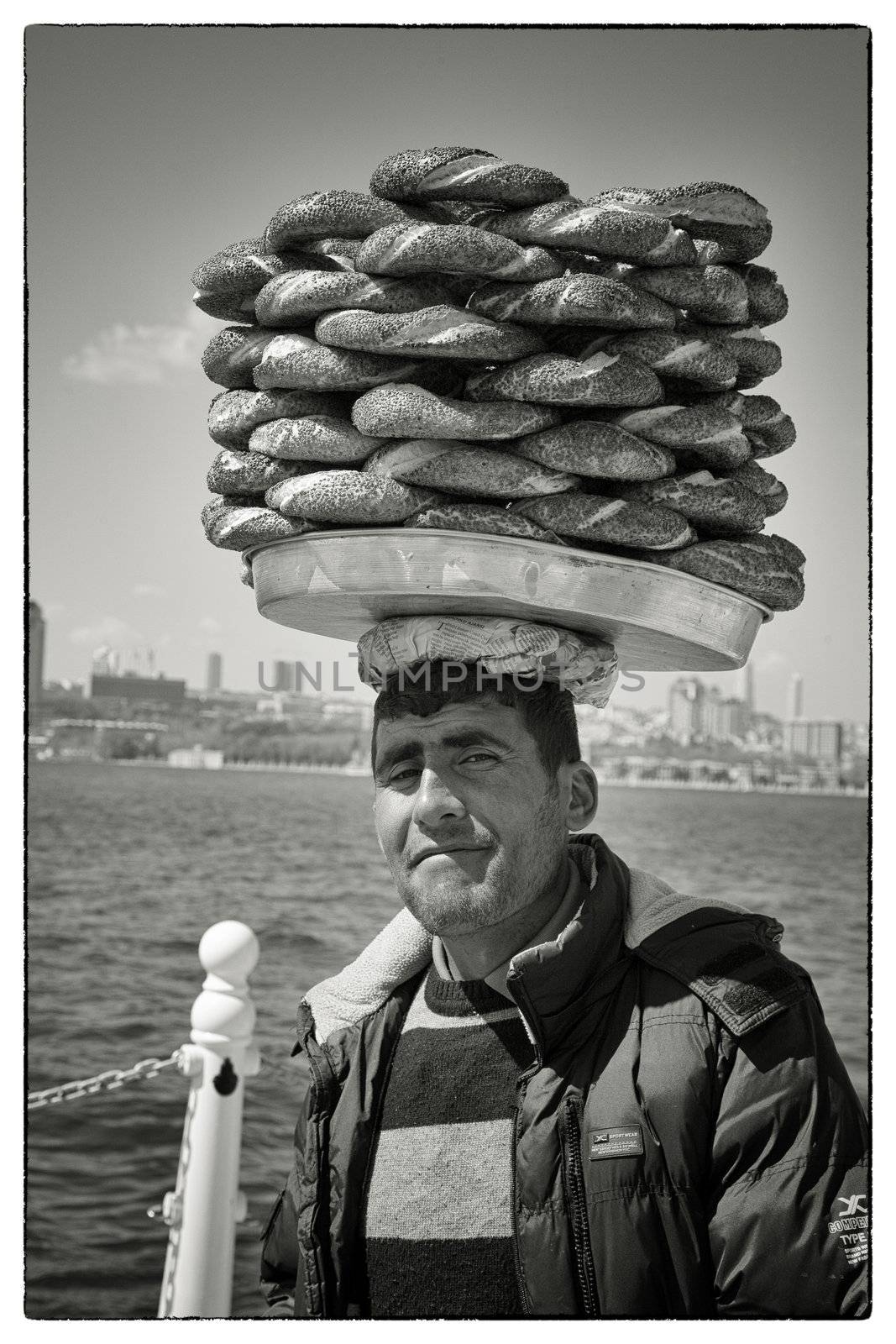 SIMIT VENDOR BOSPHORUS, ISTANBUL, TURKEY, APRIL 16, 2012: Simit vendor walking along the Bosphorus with his goods on his head trying to sell the crispy rings.