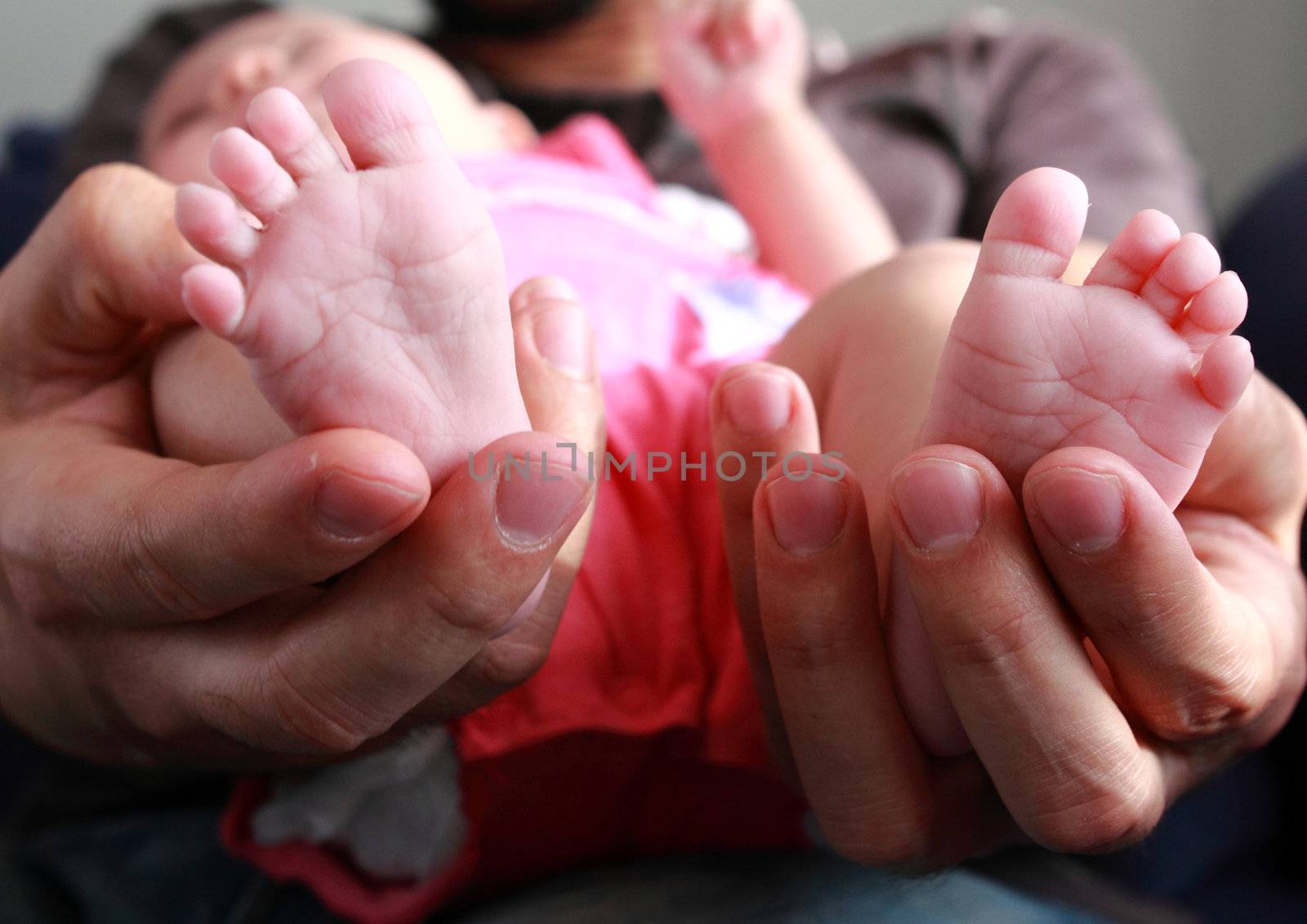 Father holding newborn sweet child feet