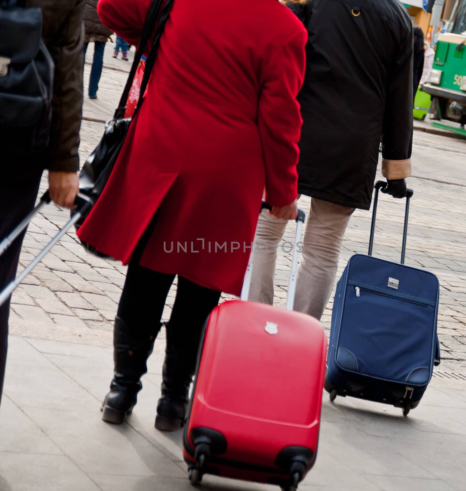 two people walking with travel cases on a street in finland