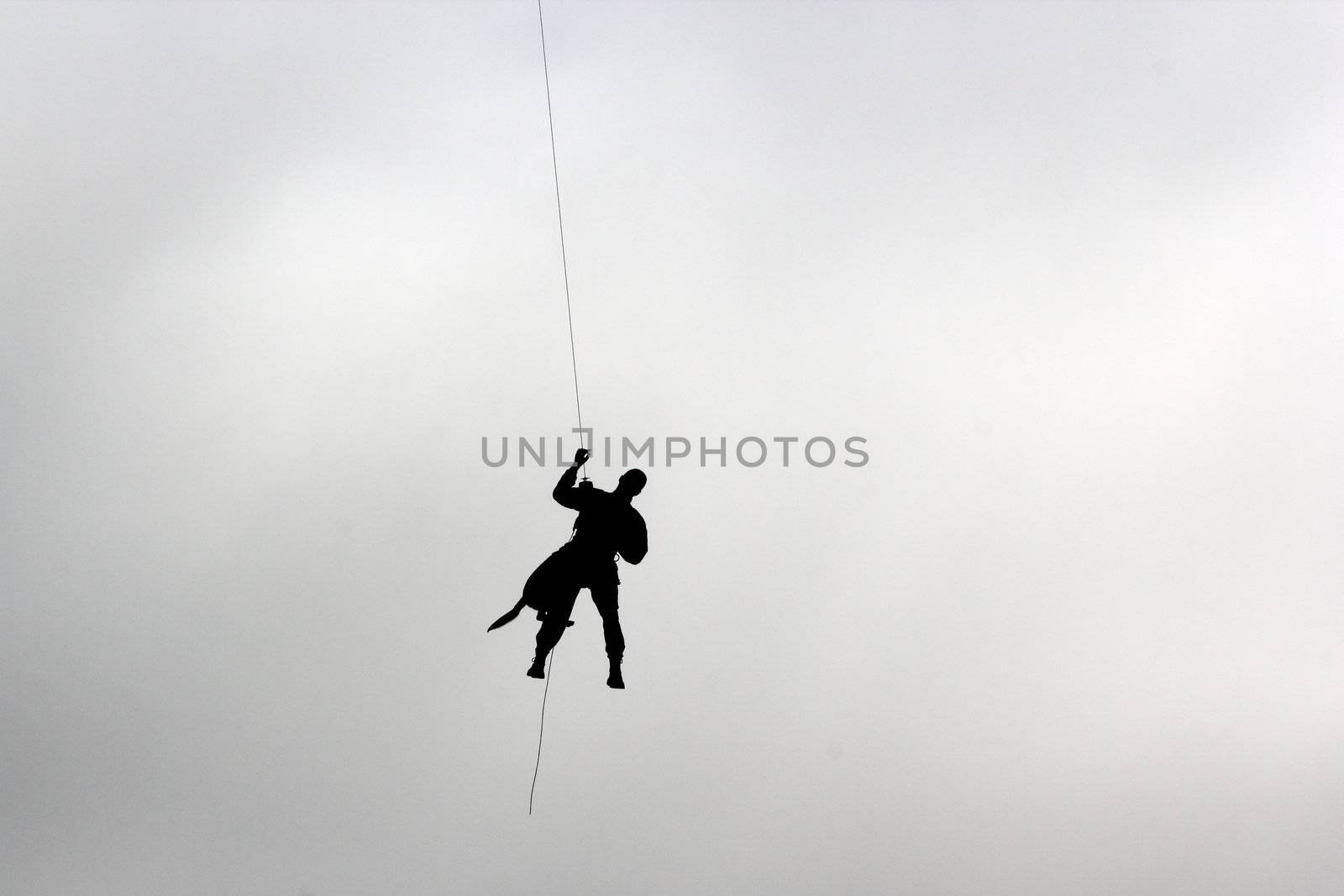 man and dog climbing down from a helicopter