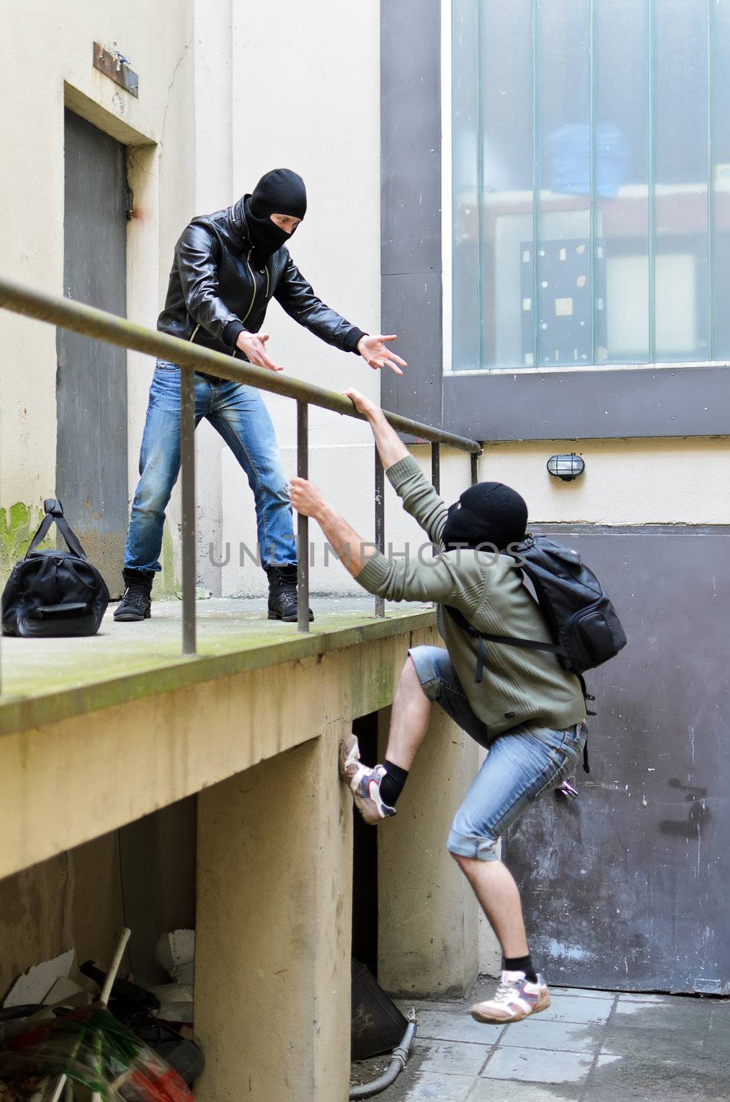 Escape from a robbery. One tries to help another to climb the rails.