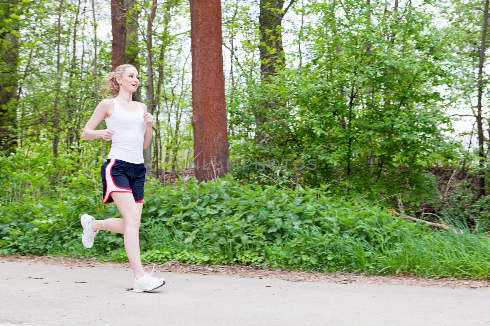young woman is jogging in forest