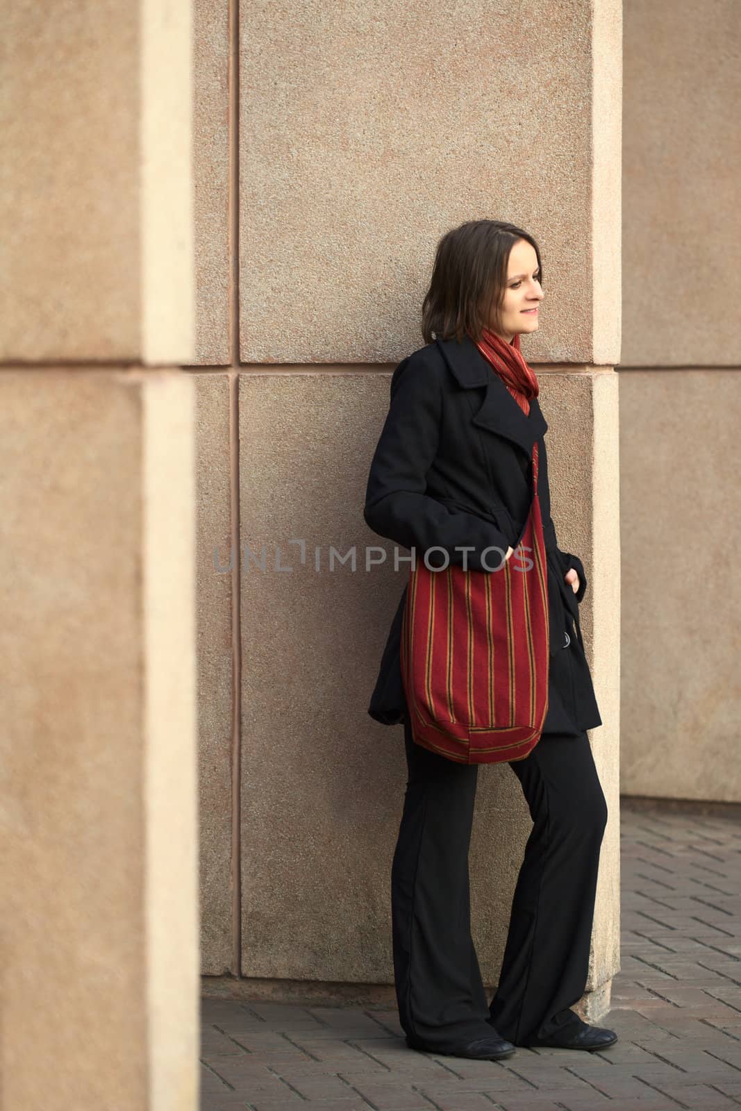 Young woman leaning against a column waiting (Selective Focus, Focus on the right eye)