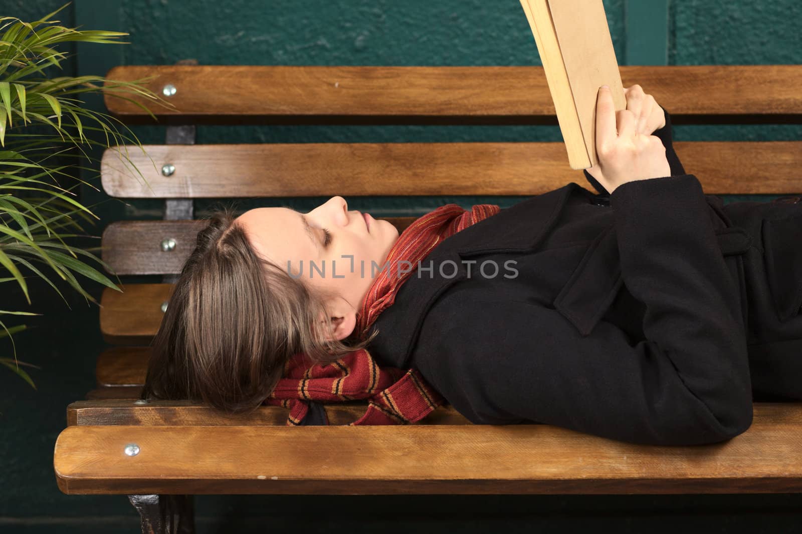 Young Caucasian woman lying on a bench reading a book (Selective Focus, Focus on the right eye) 