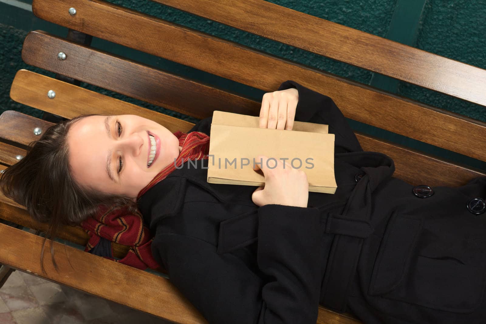 Young Happy Woman Lying on Bench Reading by sven