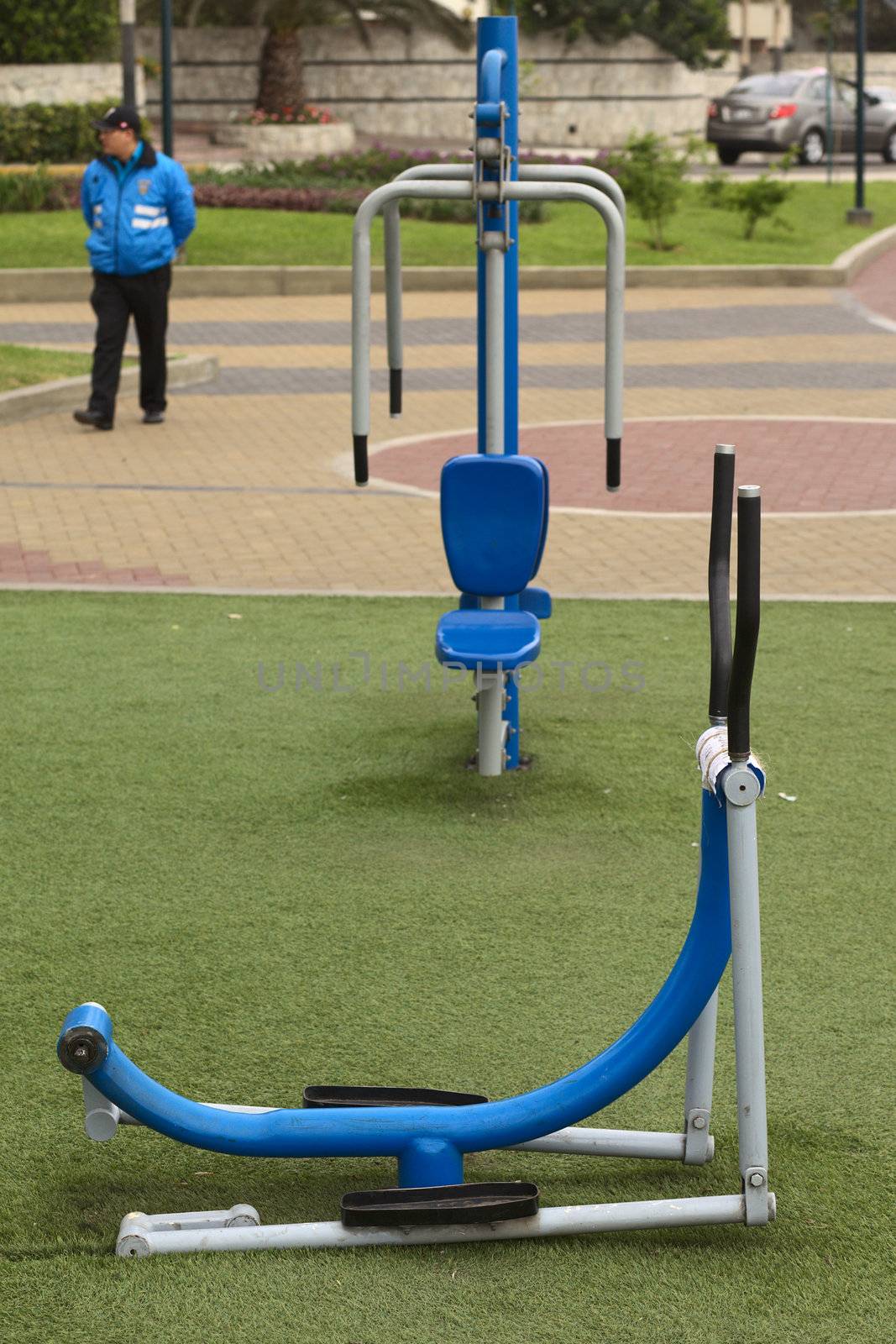 Lima, Peru - September 20, 2011: Public gym equipment along the coast in the tourist district of Miraflores, with a Seguridad Ciudadana (Citizen Security Guard) in the back. In the richest parts of Lima there is an increasing effort in offering better living conditions which includes possibilities to do exercises in public areas.  