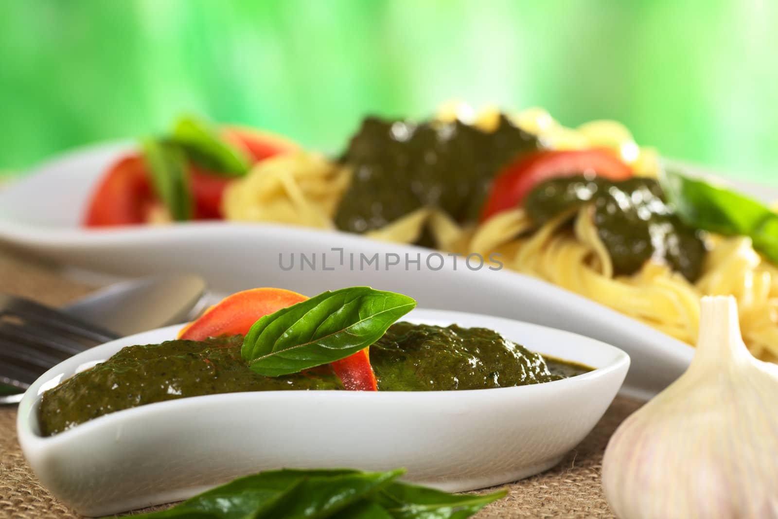 Fresh pesto made of basil and garlic garnished with fresh basil leaf and tomato slice (Selective Focus, Focus on the upper part of the basil leaf)