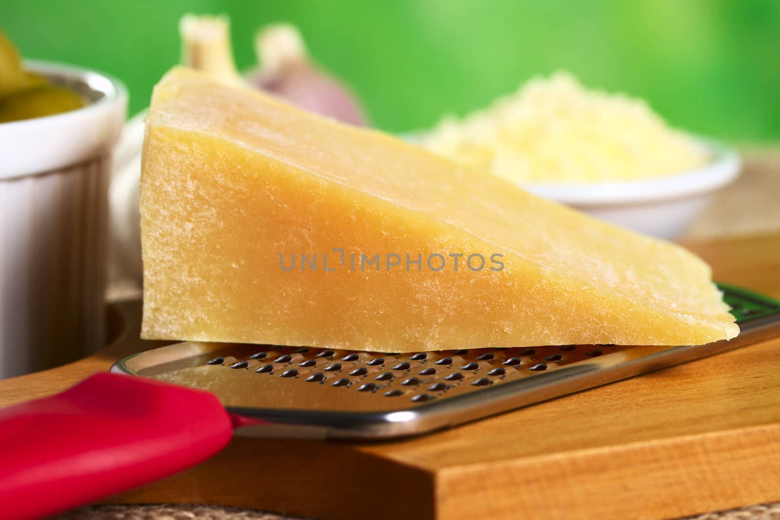 Italian hard cheese with rasp on wooden board (Selective Focus, Focus on the end of the cheese on the right)