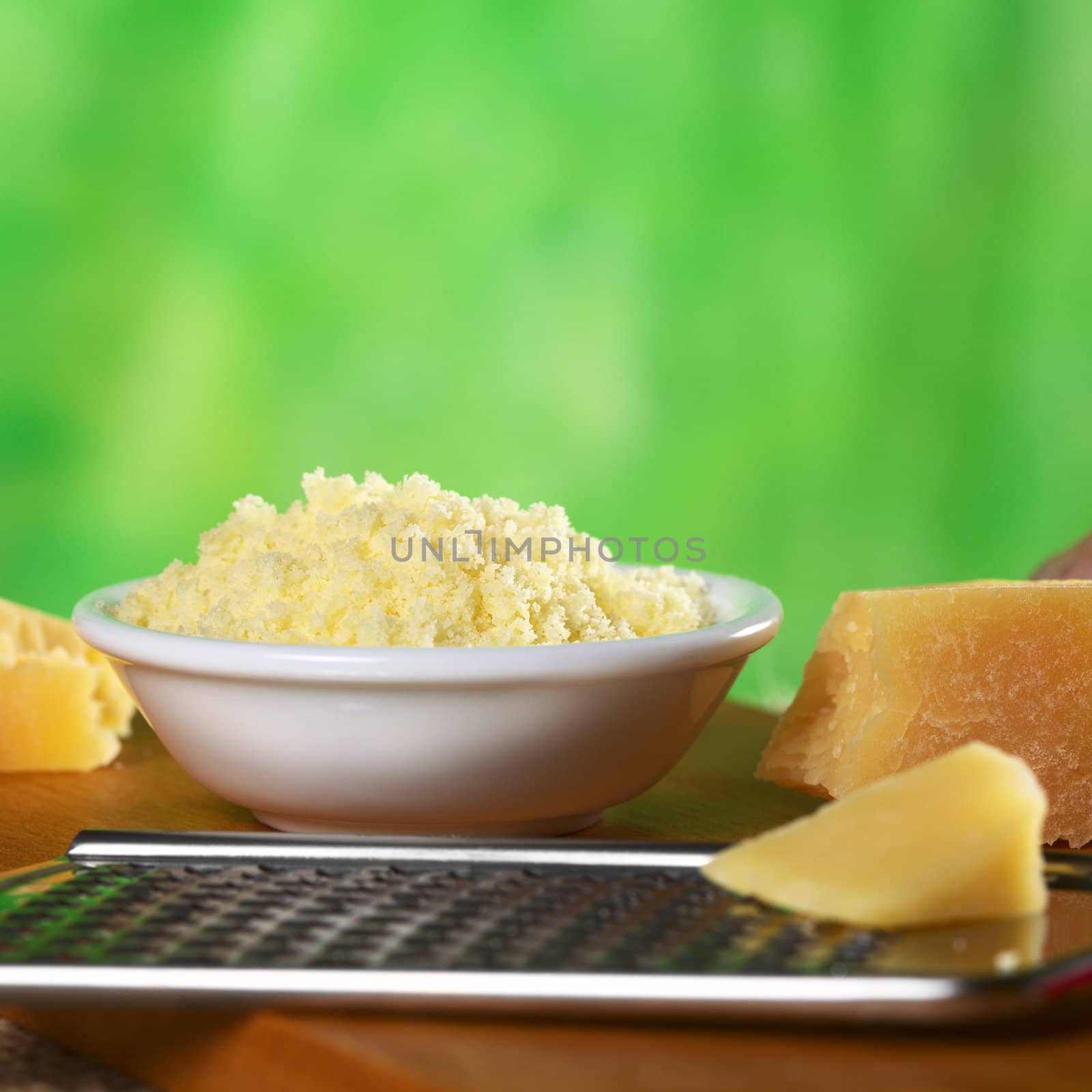 Grated Italian hard cheese with rasp in front (Selective Focus, Focus one third into the grated cheese)