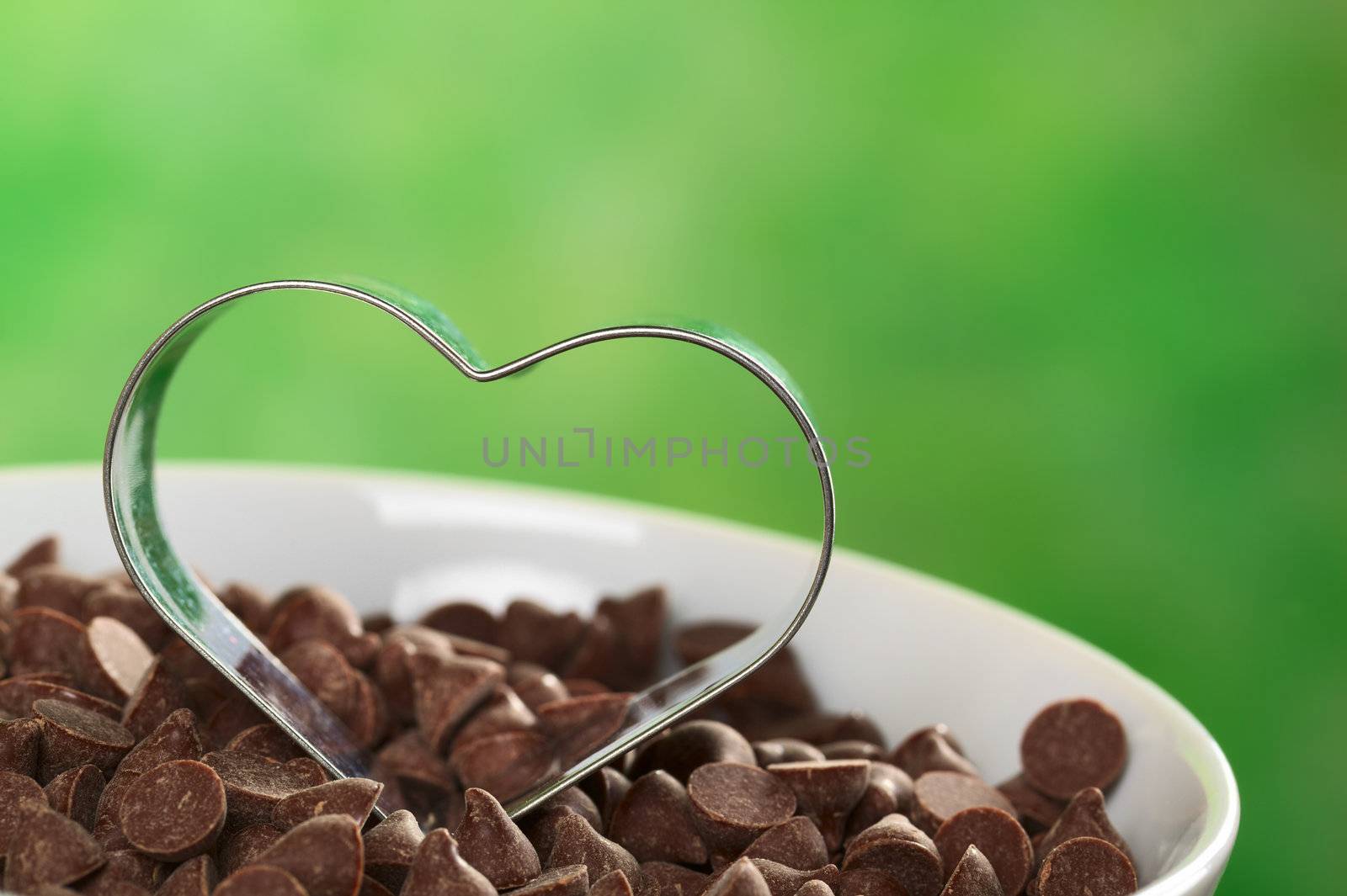 Heart-shaped cookie cutter on chocolate chips (Selective Focus, Focus on the front of the cookie cutter) 