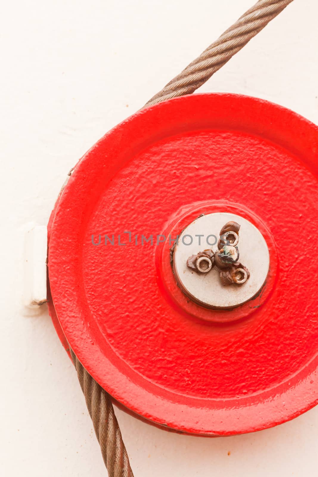 The red fairlead pulley has a grooved rim and is used as a guide around which the cable can pass in order to change direction of the pull on the load