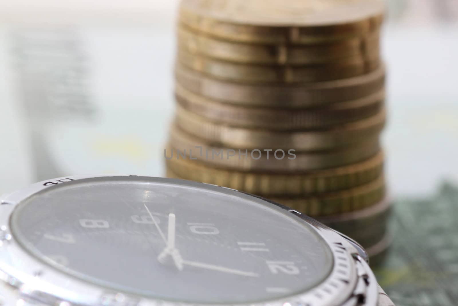 Time is money - watch in front of pile of euro coins