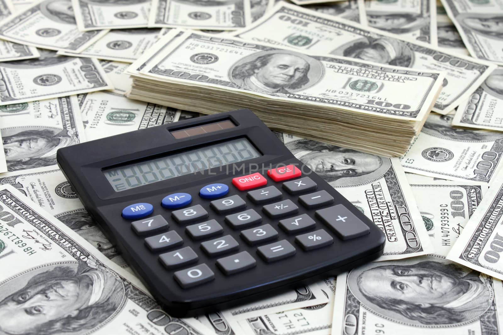 calculating income: calculator near a pile of dollars