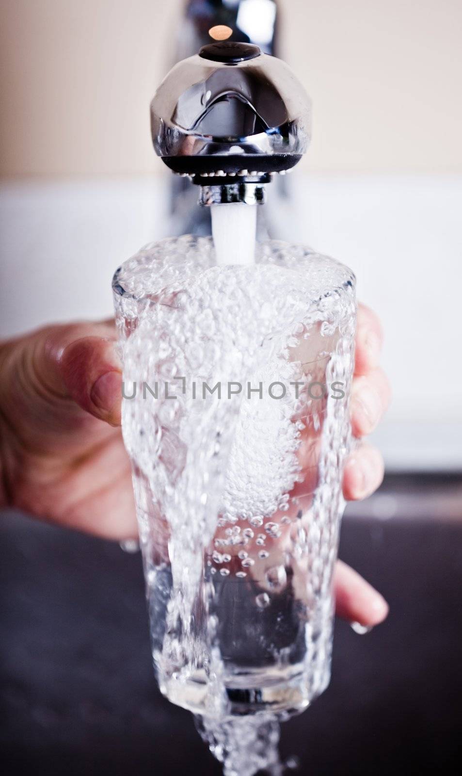 Thirsty man filling an overflowing glass of water
