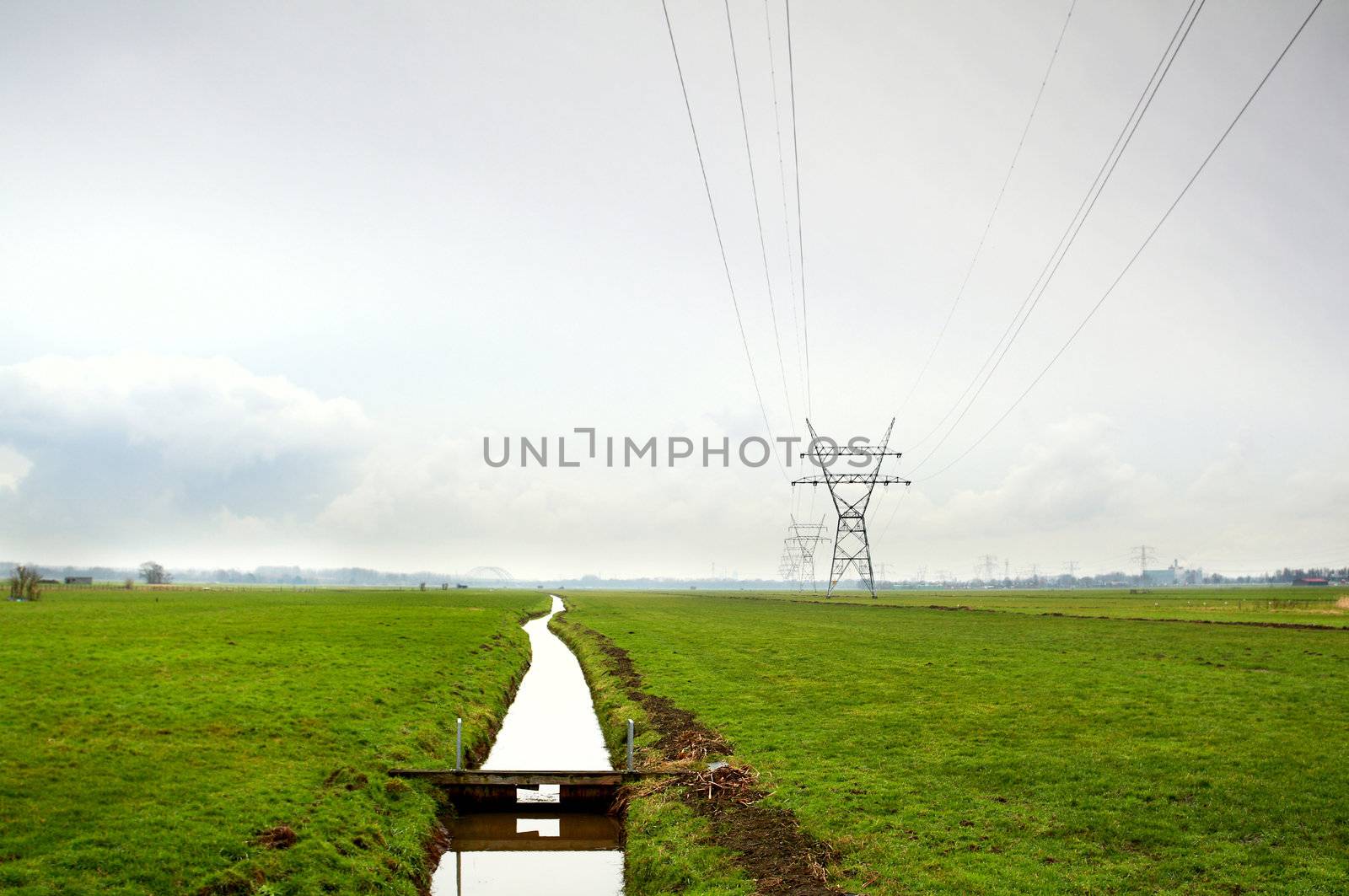 Dutch typical rural flat landscape with channel and high-voltage line 