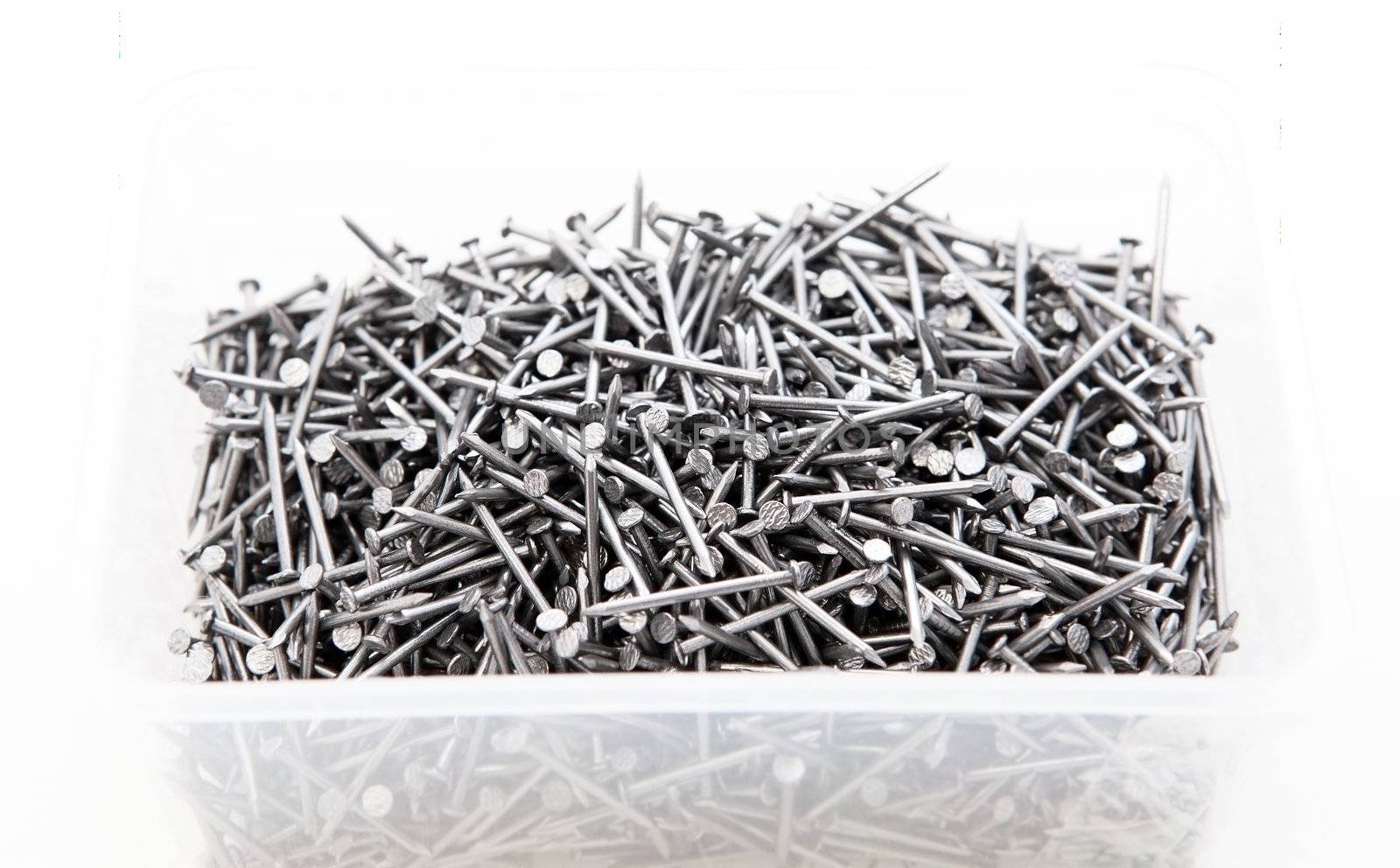 many metal nails in transparent box over white background