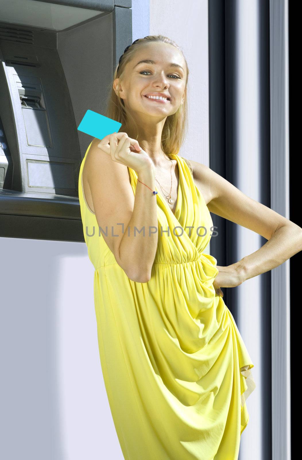 Attractive young woman withdrawing money from credit card at ATM