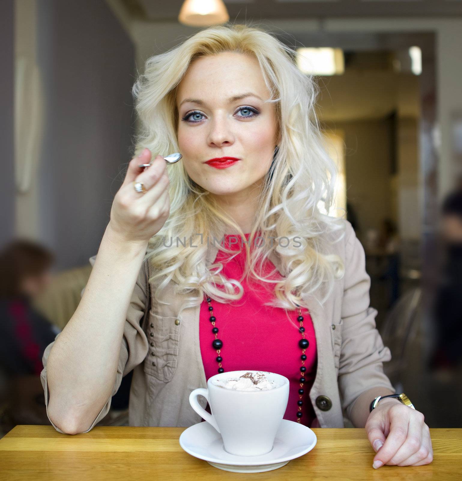 young blonde in cafe at little table with cup of coffee