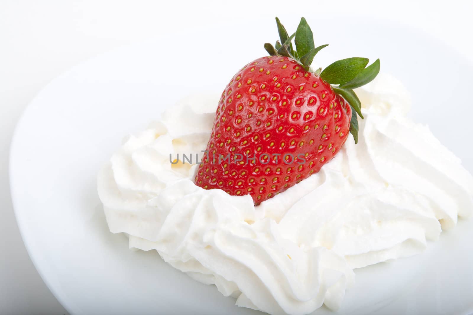 a strawberry in whipped cream on an saucer
