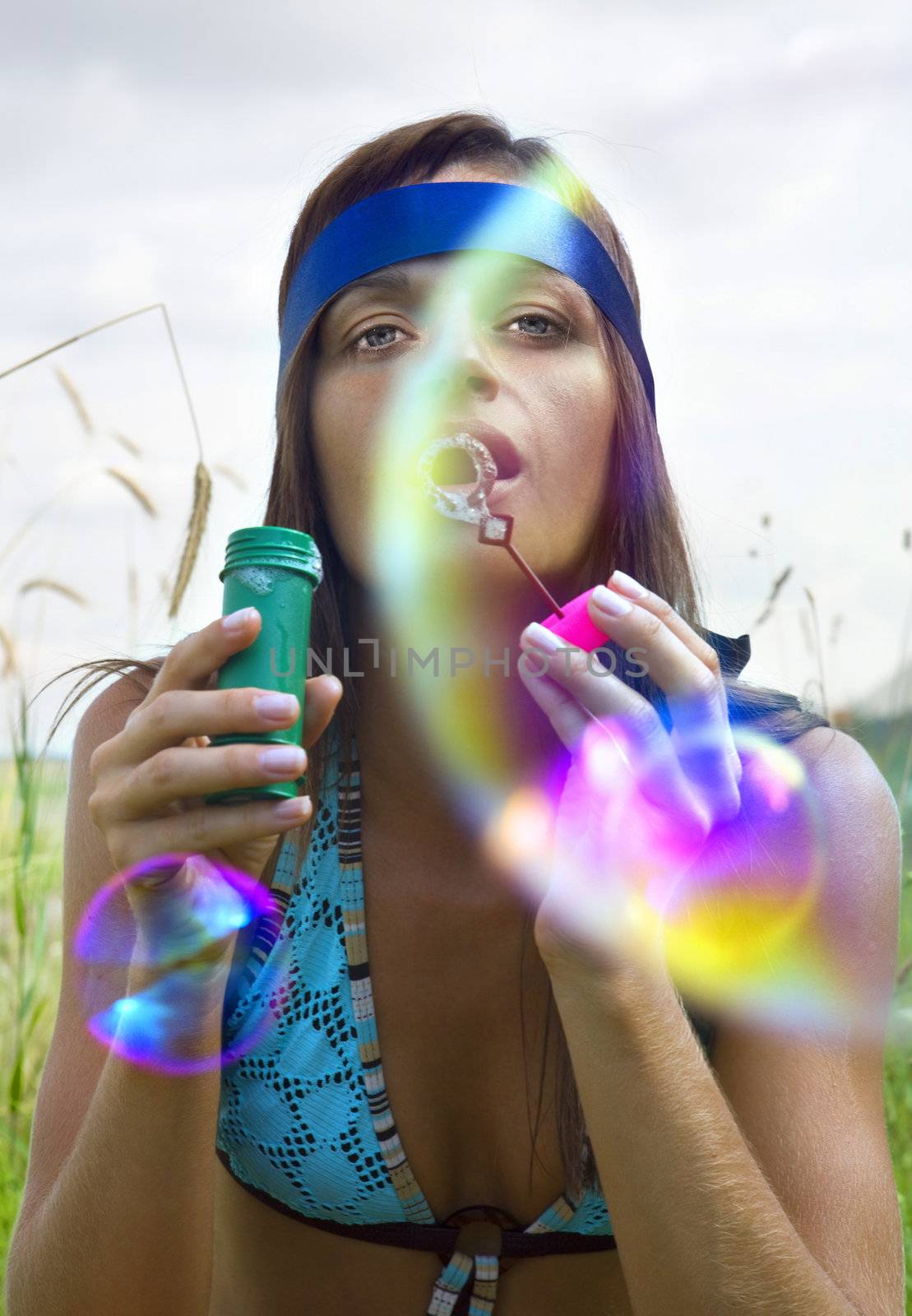 wistful young woman blowing soap bubbles at summer