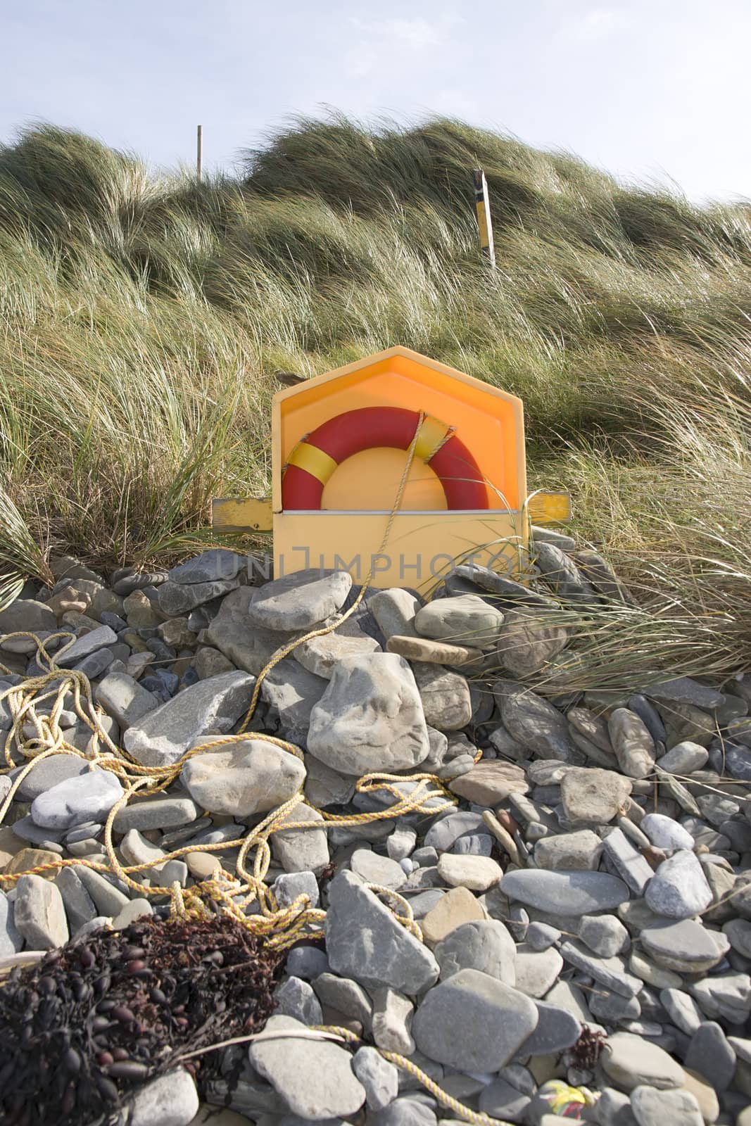 lifebuoy on rocky beal beach in county Kerry Ireland with dunes in background