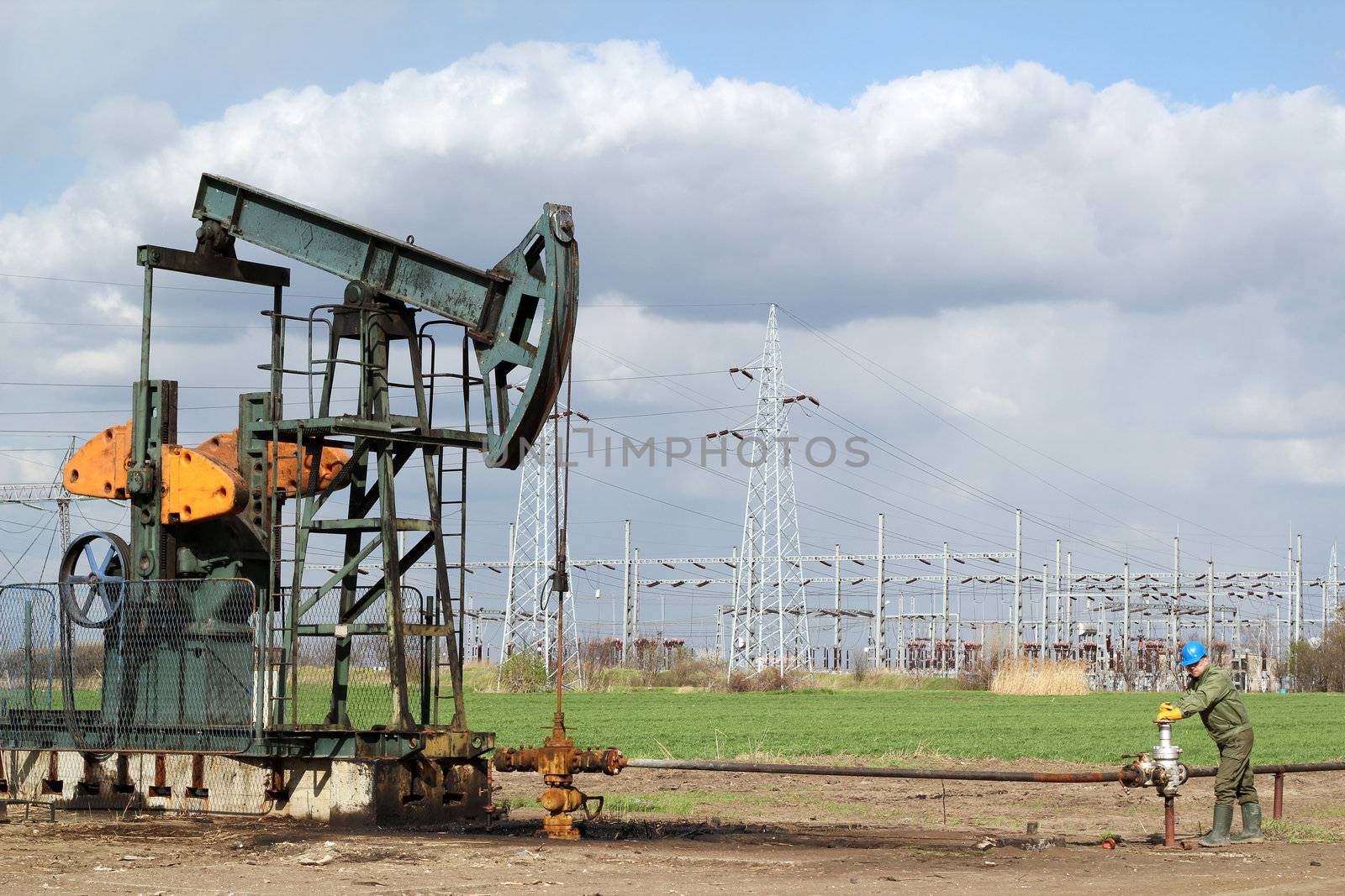 oil field with pumpjack and oil worker